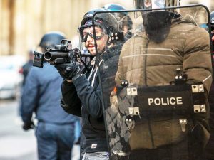 Two police officers use shield during riot control